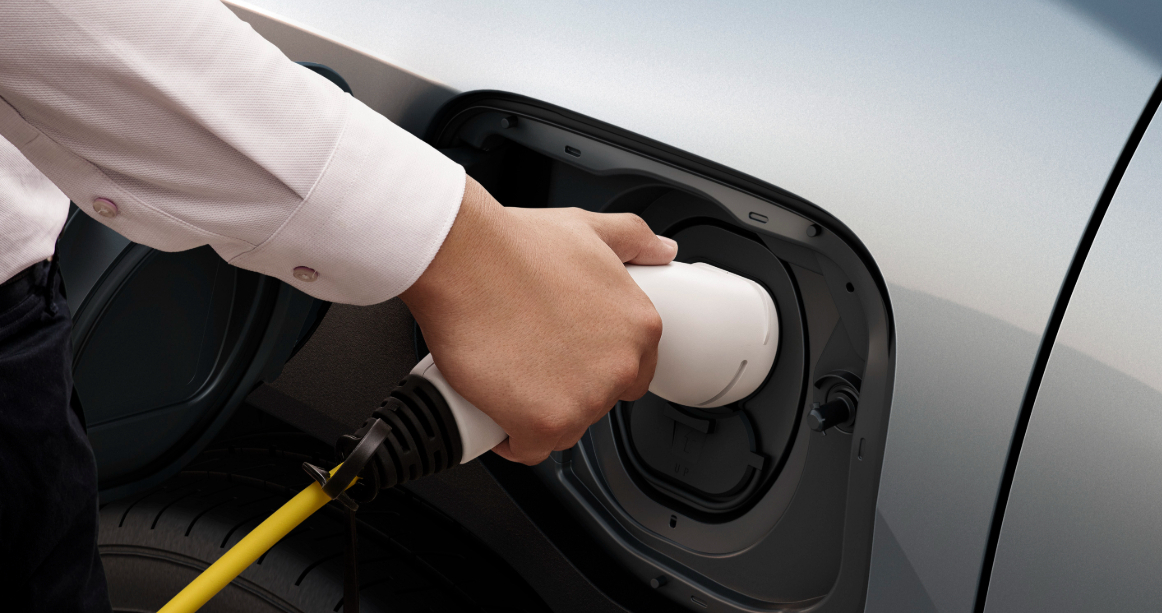 A man charging a Suzuki eVitara